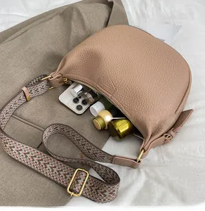 Spacious interior of khaki pebble leather crescent bag showing daily essentials and wide strap