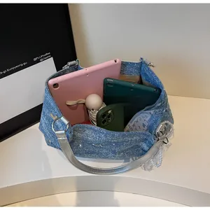 Macro view of blue denim handbag interior holding a tablet and a folding umbrella