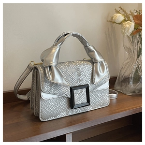 Detail of silver snake skin pattern handbag with decorative knot handle and metal buckle