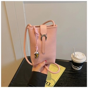 Close-up of pink litchi grain leather mini bag with silver heart charm and metal buckle