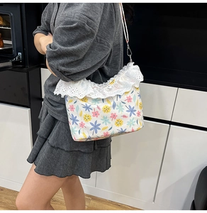 Detail of floral crossbody bag with white embroidery lace trim and adjustable strap