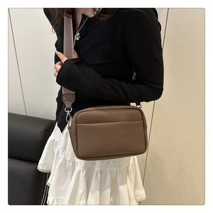 Detail of lychee pattern leather crossbody bag with striped wide shoulder strap
