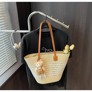 Detail of straw woven tote bag featuring diamond hollow mesh and a cute plush bear charm