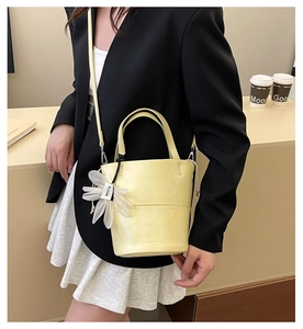 Close-up of pale yellow bucket bag with fine leather texture and daisy flower charm