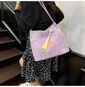 Detail of lavender silk tote bag with floral embroidery and long yellow tassel