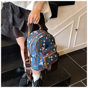 Detailed view of mini denim backpack featuring colorful star embroidery and leather handle