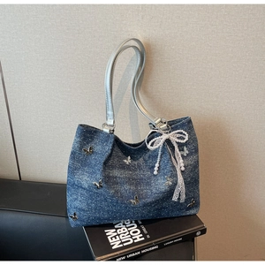Close-up of blue denim tote bag with silver butterfly charms and white lace bow