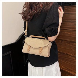 Detail of woven texture beige crossbody bag with belt buckle flap and top handle
