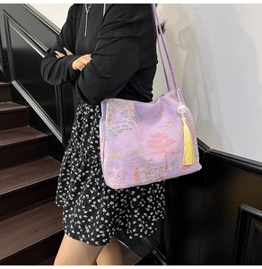 Close-up of purple satin tote with traditional landscape embroidery and yellow tassels