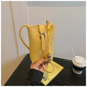 Detail of yellow pebbled leather bucket bag with silver buckle in a cafe setting
