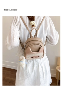 Rear view of a khaki cartoon cat mini backpack with cat ears and a plush charm on model
