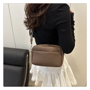 Detail of a brown lychee pattern PU leather crossbody bag with wide adjustable strap