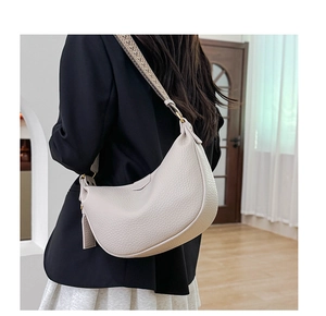 Beige crescent bag with wide jacquard strap shown on model for a casual modern look
