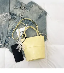 Flat lay of bright yellow bucket bag with floral charm on blue denim jacket