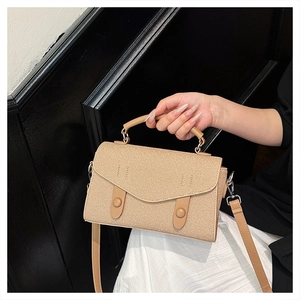 Detail of beige woven crossbody bag with decorative straps and round buttons for women