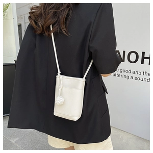 Detailed shot of white lychee leather mini crossbody bag with woven knot strap decoration