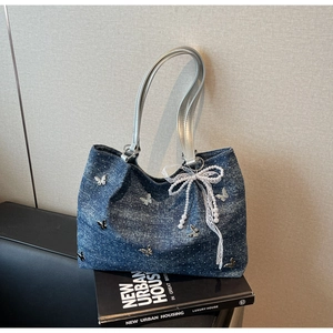 Detail of blue denim tote bag with silver butterfly charms and pearl bow decoration