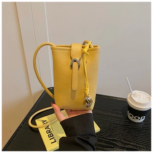 Detail of yellow lychee pattern leather phone bag with silver buckle and braided knots
