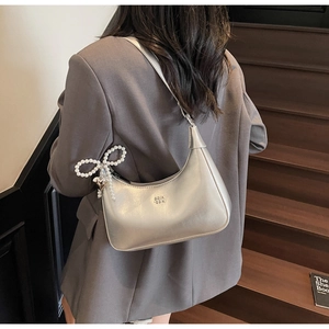 Detail of silver hobo bag with pearl bow charm and SOIN LOVE brand embossing