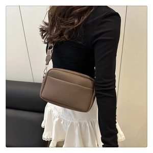 Detail of dark brown litchi pattern PU leather crossbody bag with striped wide strap