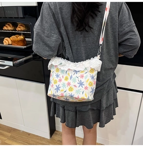 Detailed shot of floral canvas crossbody bag with white lace trim and metal hooks