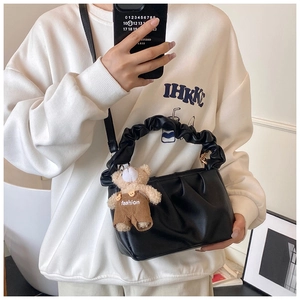 Detail of black pleated cloud bag with removable shoulder strap and cute bear charm