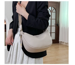 Detail of cream crescent crossbody bag featuring lychee grain leather and jacquard strap