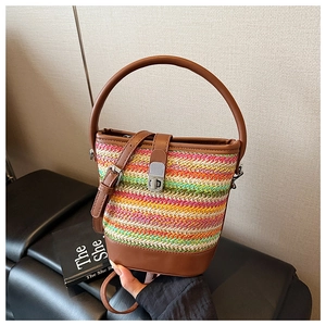 Detail of colorful rainbow woven straw bucket bag with brown faux leather trim and metal lock