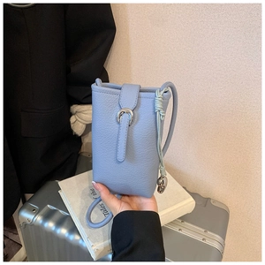 Close-up of light blue pebble leather bucket bag with silver buckle and heart charm