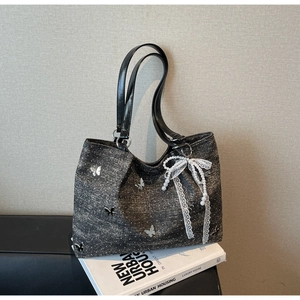 Detail of grey denim shoulder bag with white butterfly print and pearl lace charm