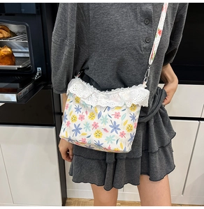 Detailed close-up of floral crossbody bag with white lace trim and colorful flower pattern