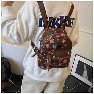 Rear view of model wearing a brown backpack with colorful embroidered stars and main zipper