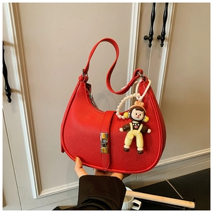 Detail of red hobo bag featuring litchi grain texture, pearl chain, and cartoon charm