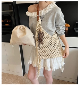 Détail d'un sac cabas en maille fait main avec pompon et bandoulière en cuir souple