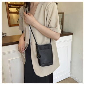 Detail of black litchi grain leather mini crossbody bag with manual knotted strap detail