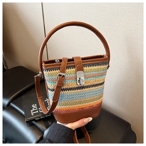 Detail view of rainbow striped woven bucket bag with brown leather trim and metal twist lock