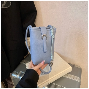 Detail of light blue pebble leather bucket bag with silver buckle and braided tassel