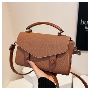 Close-up of vintage brown woven handbag featuring premium leather straps and silver hardware