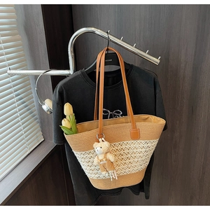 Detail of woven straw tote bag featuring contrast hollow patterns and cute bear charm