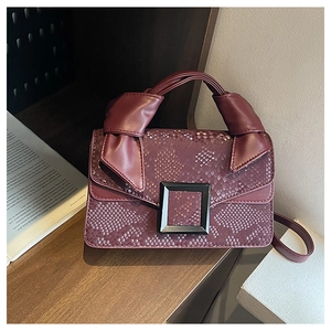 Détail du sac rouge bordeaux à motif serpent avec boucle noire et poignée nouée élégante