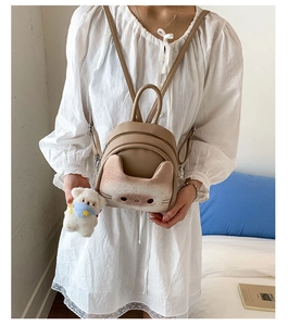 Detailed close-up of khaki cat-shaped mini backpack with fluffy bear charm on model