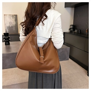 Detailed view of brown faux leather hobo bag worn over the shoulder in minimalist home
