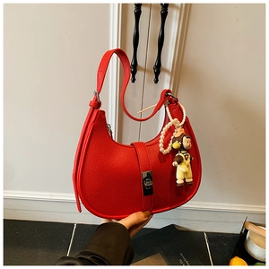 Detail of red pebbled leather crescent bag with pearl strap and cartoon monkey charm