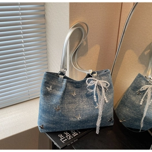 Close-up of blue denim tote bag with silver butterfly appliques and pearl lace charm