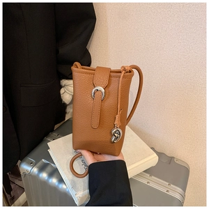 Detail of brown litchi pattern leather phone bag with horseshoe buckle and heart pendant