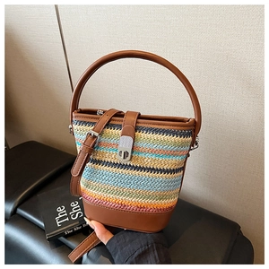 Detail view of rainbow woven straw bucket bag with brown leather trim and metal twist lock