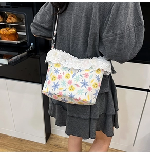 Detail of floral canvas crossbody bag with white lace trim and adjustable strap