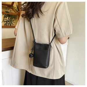 Detail of black textured leather mini crossbody bag with unique knot ball strap accessory