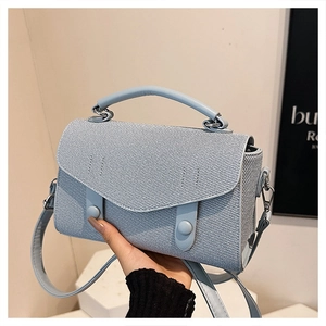 Detail of light blue crossbody bag with twill texture and decorative buttons