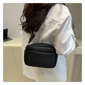 Detailed back view of a black lychee texture crossbody bag with striped wide strap